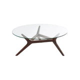 Table basse Maricielo à plateau rond en verre et piètement en noyer massif, sur fond blanc
